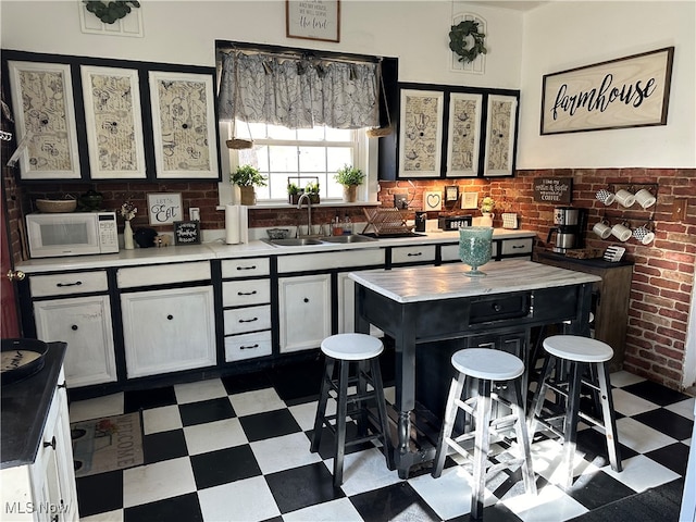 kitchen with brick wall, sink, decorative backsplash, and a kitchen island