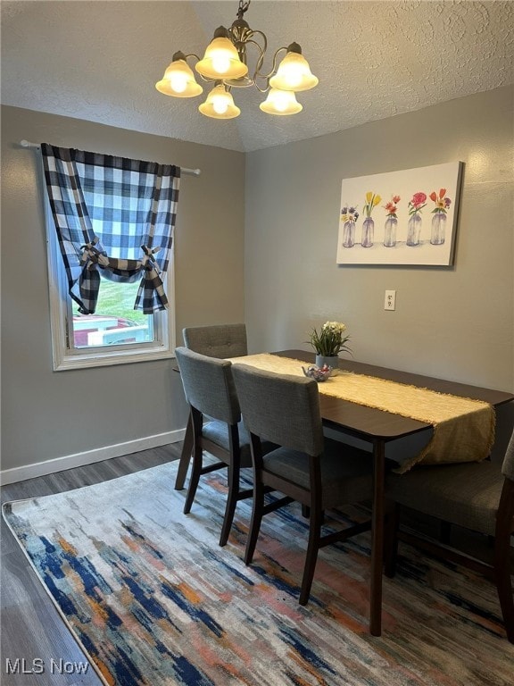 dining room featuring dark wood-type flooring, a textured ceiling, and a chandelier