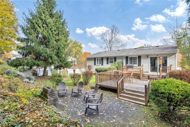 rear view of property featuring a wooden deck and a patio