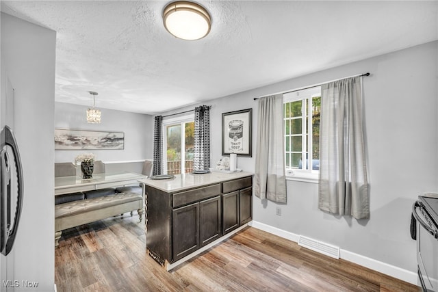 kitchen with pendant lighting, a textured ceiling, electric range, and light wood-type flooring