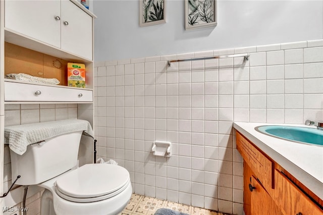 bathroom with toilet, vanity, and tile walls