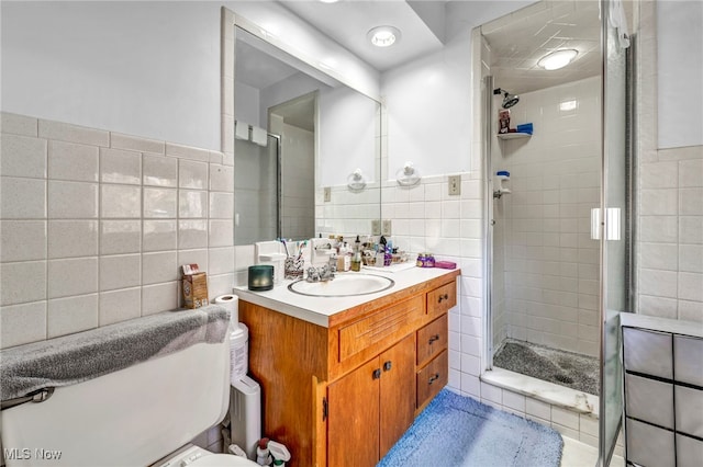 bathroom featuring vanity, a shower with shower door, toilet, and tile walls