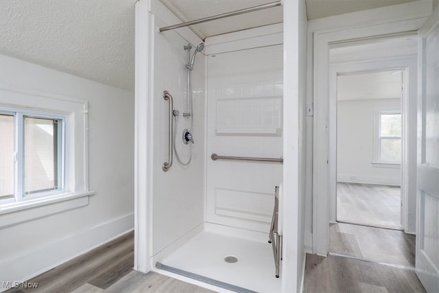 bathroom with a textured ceiling, hardwood / wood-style flooring, and a shower