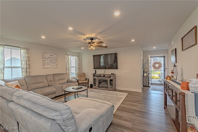 living room featuring dark wood-type flooring, ceiling fan, and a fireplace