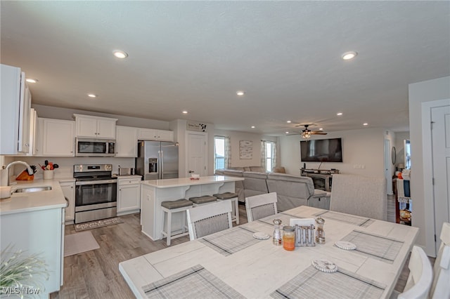 dining room featuring sink, light wood-type flooring, and ceiling fan