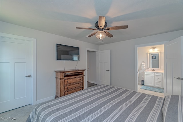 bedroom featuring ceiling fan, light carpet, sink, and ensuite bath