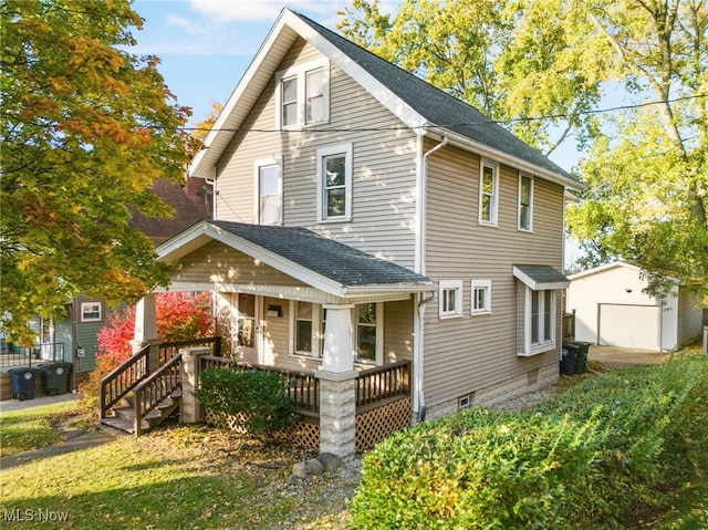 front facade with covered porch, a garage, and an outbuilding