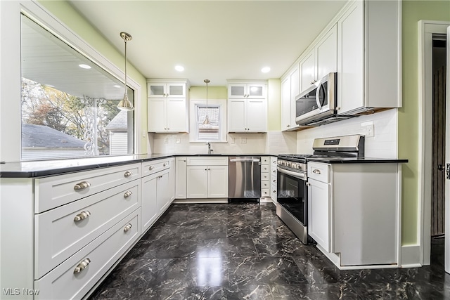 kitchen featuring appliances with stainless steel finishes, pendant lighting, tasteful backsplash, white cabinetry, and sink