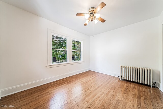 unfurnished room featuring radiator, light hardwood / wood-style flooring, and ceiling fan