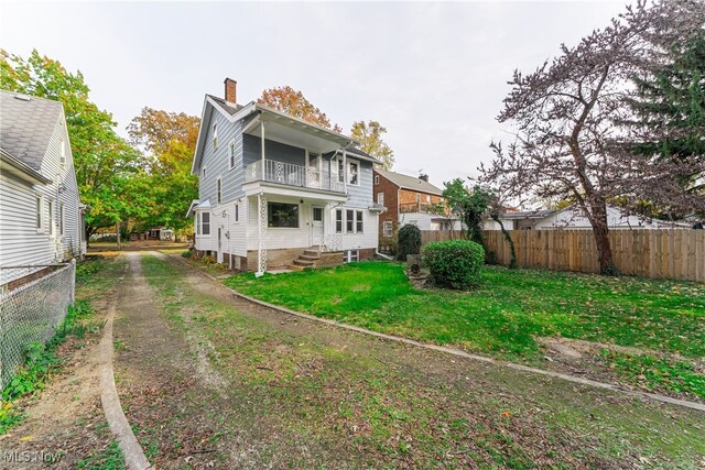 back of property featuring a lawn and a balcony