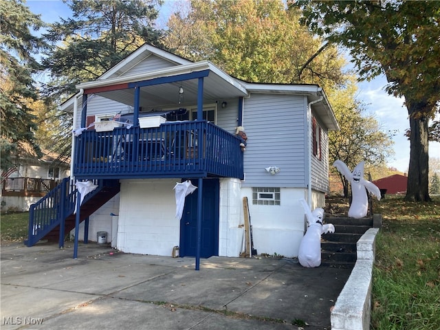 rear view of property with a wooden deck and a garage