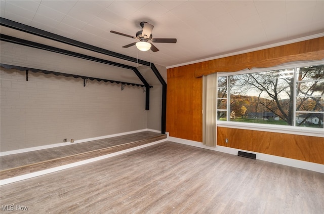 empty room with hardwood / wood-style floors, ceiling fan, and wood walls