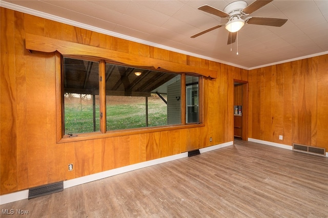 spare room with hardwood / wood-style floors, ceiling fan, crown molding, and wood walls