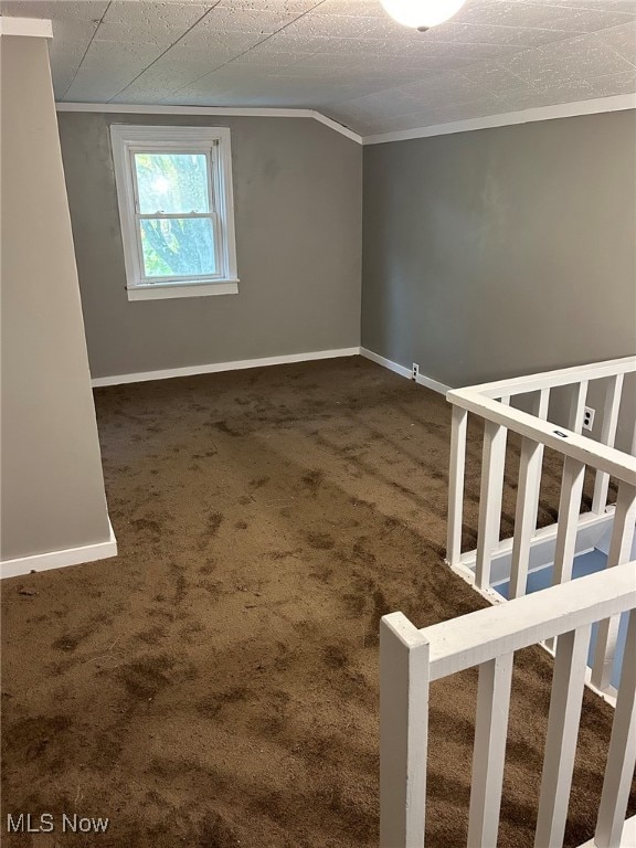 spare room with crown molding, a textured ceiling, and dark colored carpet