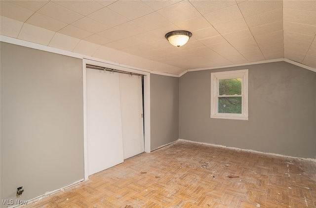 unfurnished bedroom featuring a closet, light parquet floors, and vaulted ceiling