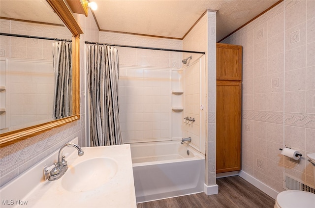 full bathroom with a textured ceiling, hardwood / wood-style flooring, toilet, shower / tub combo with curtain, and sink