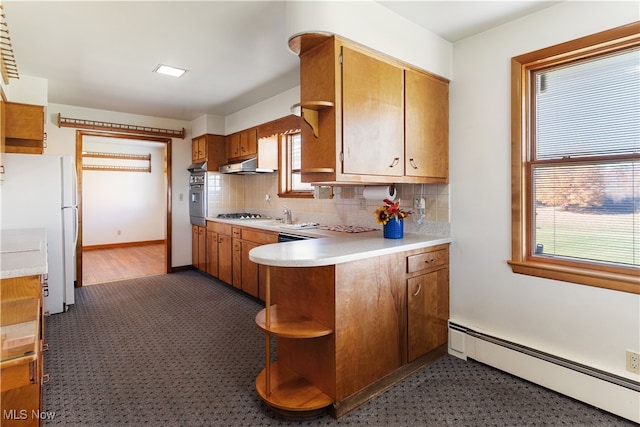 kitchen with appliances with stainless steel finishes, decorative backsplash, a baseboard heating unit, and kitchen peninsula