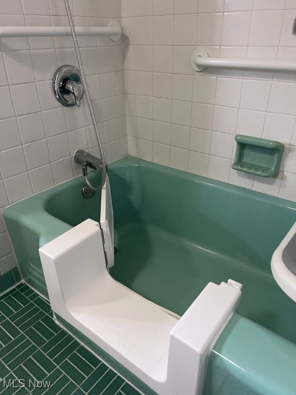 bathroom with toilet, tiled shower / bath combo, and tile patterned flooring