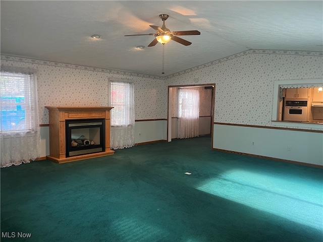 unfurnished living room featuring lofted ceiling, dark colored carpet, and ceiling fan