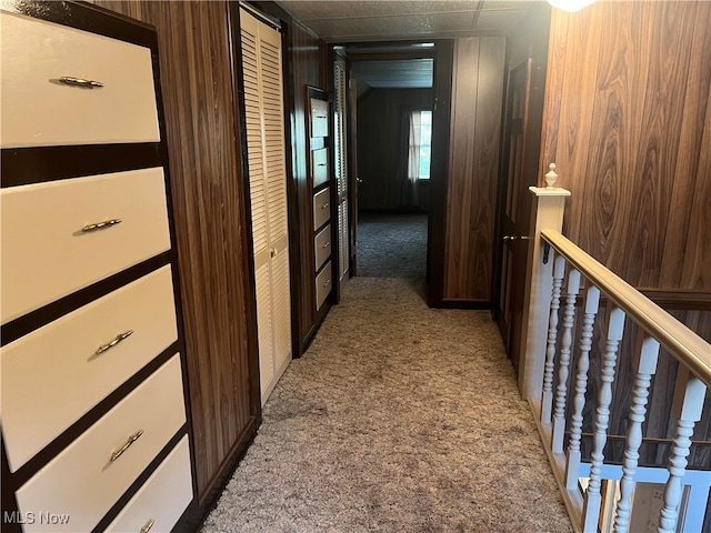 corridor with carpet flooring and wood walls