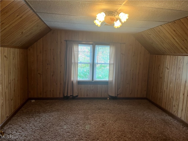 bonus room with wood walls, carpet flooring, and vaulted ceiling