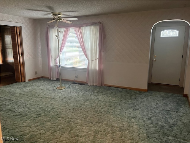 carpeted spare room featuring a textured ceiling and ceiling fan