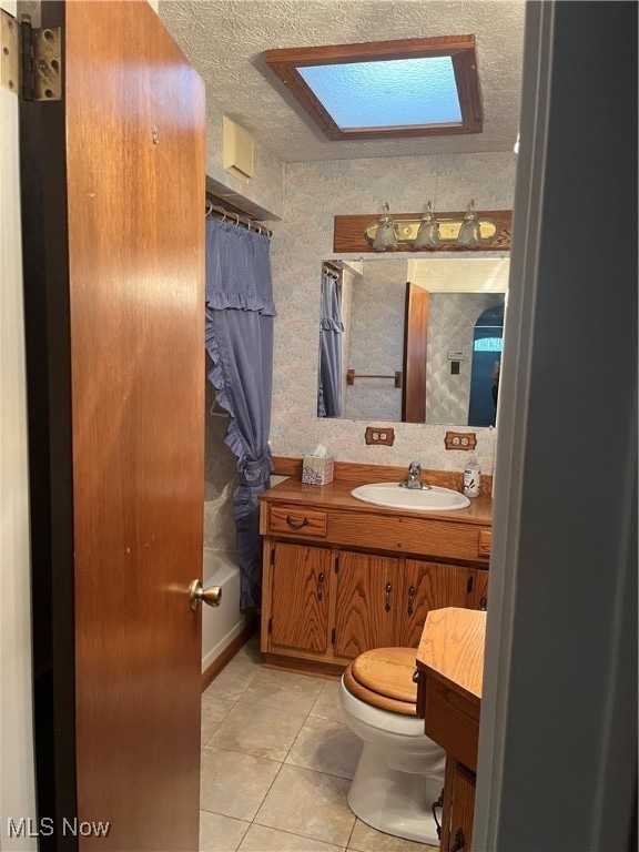 full bathroom with vanity, a textured ceiling, toilet, and a skylight