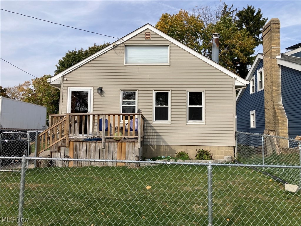 rear view of house featuring a deck and a lawn