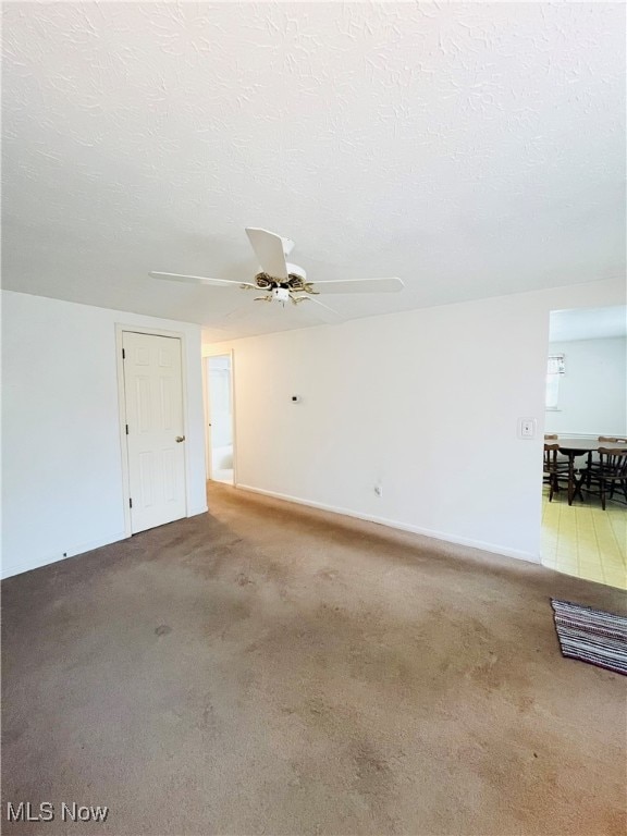 empty room with ceiling fan, a textured ceiling, and carpet floors