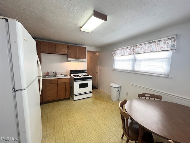 kitchen with a textured ceiling, sink, and white appliances