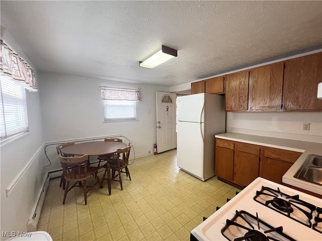 kitchen featuring baseboard heating, a textured ceiling, and white appliances