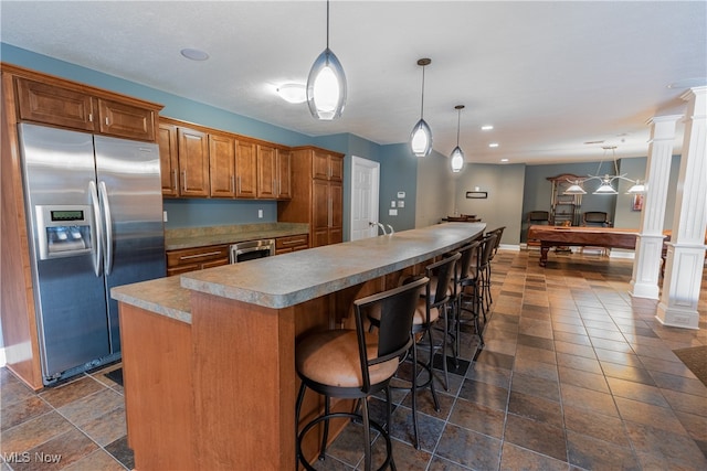 kitchen with a kitchen island, stainless steel fridge with ice dispenser, ornate columns, and pendant lighting