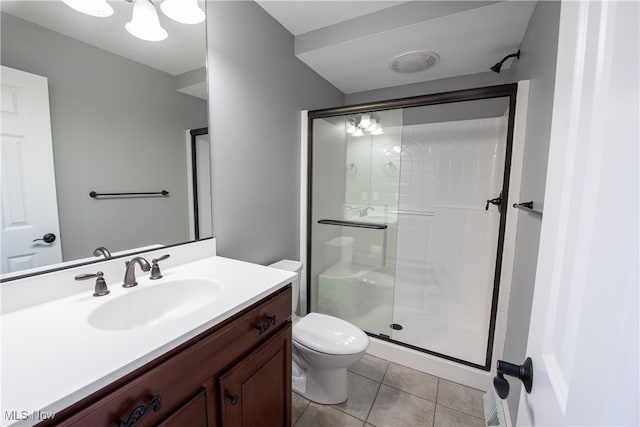 bathroom featuring a shower with door, vanity, toilet, and tile patterned flooring