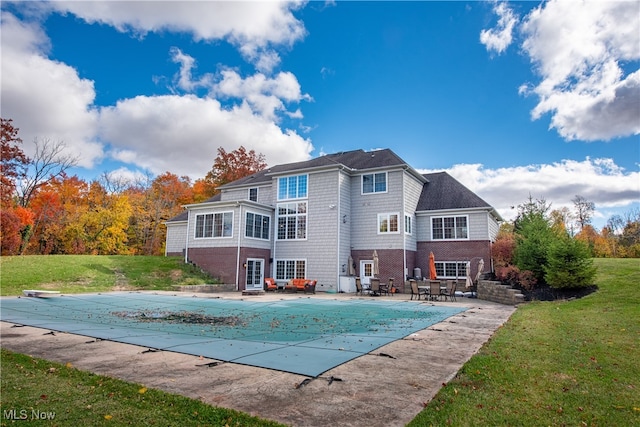 rear view of house with a yard, a covered pool, and a patio