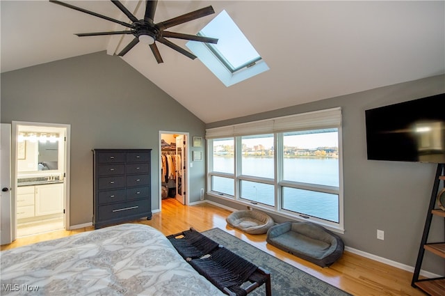 bedroom with ceiling fan, connected bathroom, light wood-type flooring, a closet, and a walk in closet