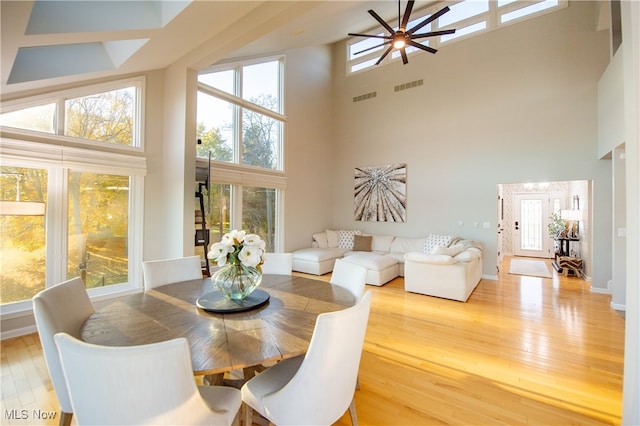 dining room with a towering ceiling, a healthy amount of sunlight, and wood-type flooring