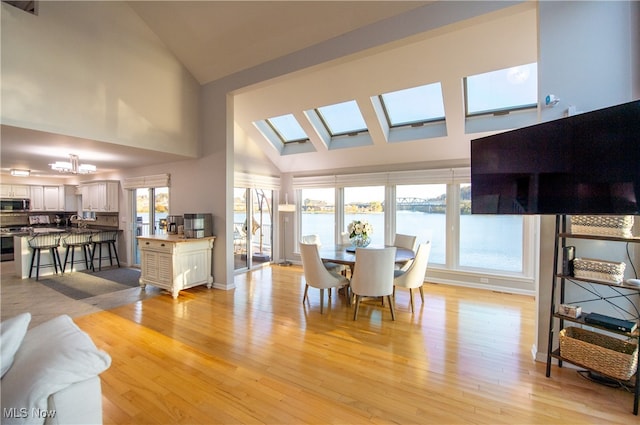 dining area with high vaulted ceiling and light wood-type flooring