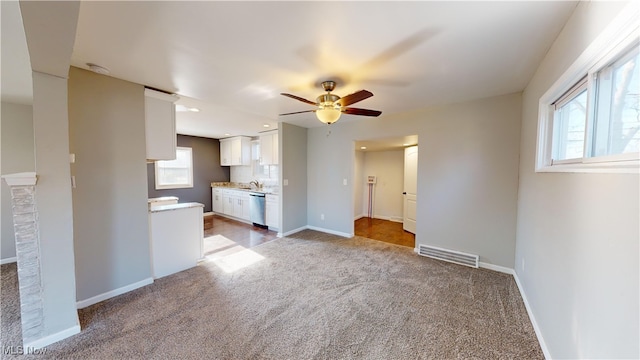 unfurnished living room with ceiling fan, carpet flooring, and sink