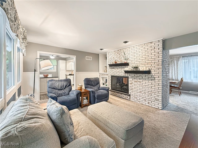 carpeted living room with ceiling fan and a fireplace