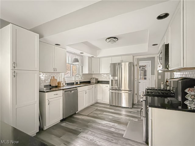 kitchen featuring sink, stainless steel appliances, dark hardwood / wood-style flooring, backsplash, and white cabinets