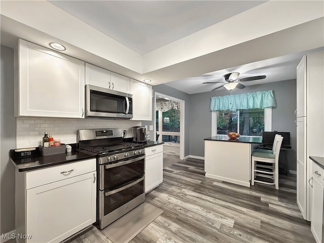 kitchen featuring decorative backsplash, white cabinets, dark wood-type flooring, and appliances with stainless steel finishes