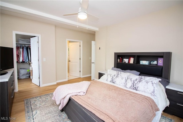 bedroom with ceiling fan, a spacious closet, light hardwood / wood-style flooring, and a closet