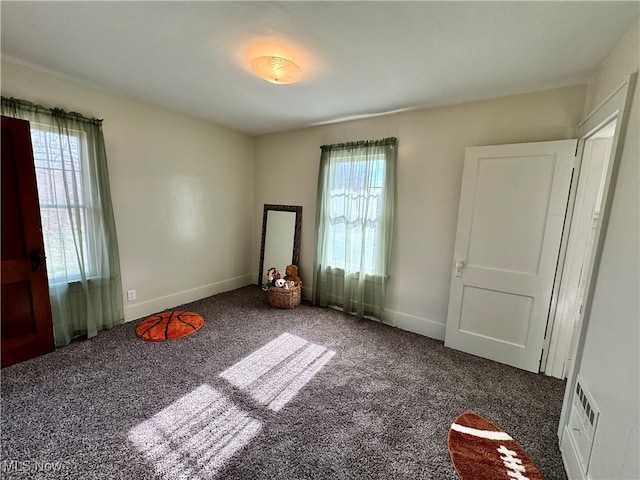 interior space featuring dark carpet and plenty of natural light