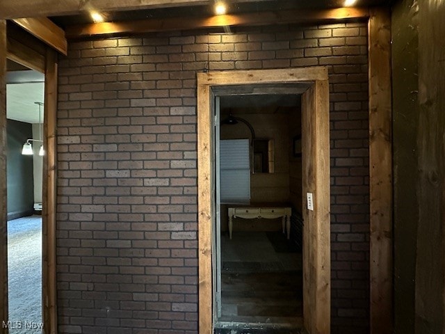 hallway featuring carpet flooring and brick wall