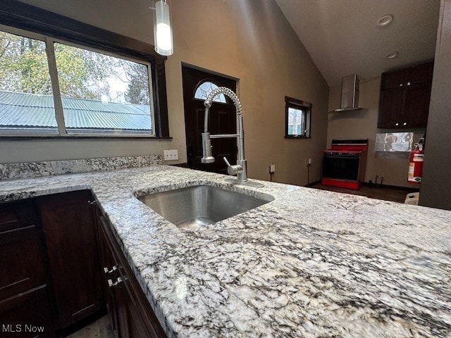 kitchen featuring wall chimney range hood, range with electric cooktop, dark brown cabinetry, sink, and lofted ceiling