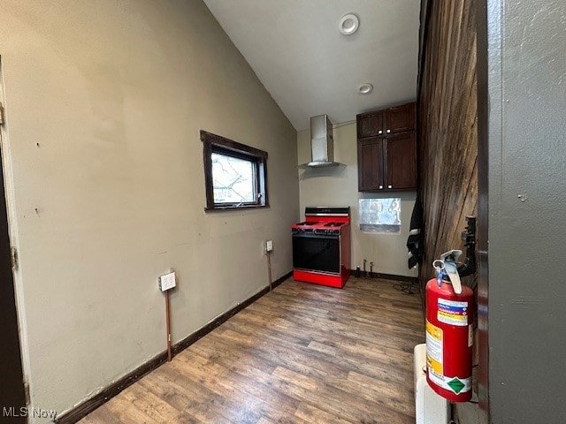 kitchen featuring vaulted ceiling, hardwood / wood-style flooring, wall chimney range hood, dark brown cabinets, and white range