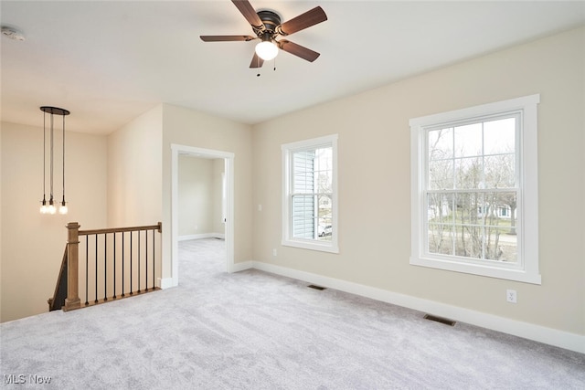 carpeted spare room featuring ceiling fan and a healthy amount of sunlight