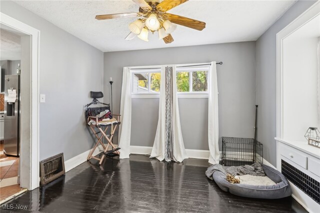 misc room featuring dark wood-type flooring, a textured ceiling, and ceiling fan