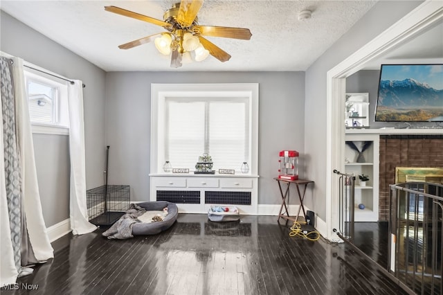 miscellaneous room with radiator, ceiling fan, wood-type flooring, and a textured ceiling