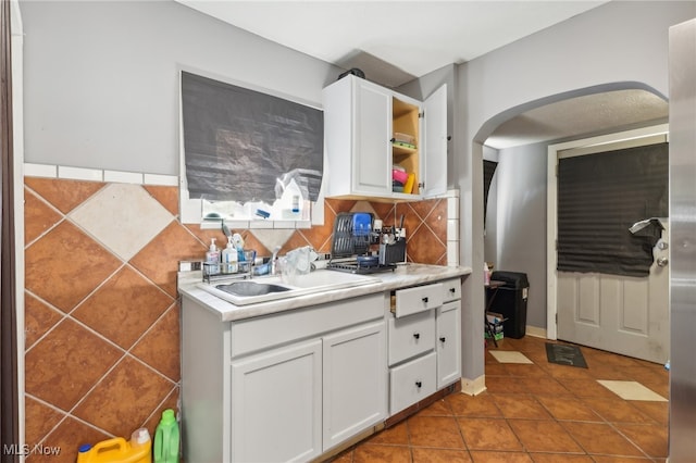 kitchen featuring sink, white cabinetry, backsplash, and tile patterned flooring